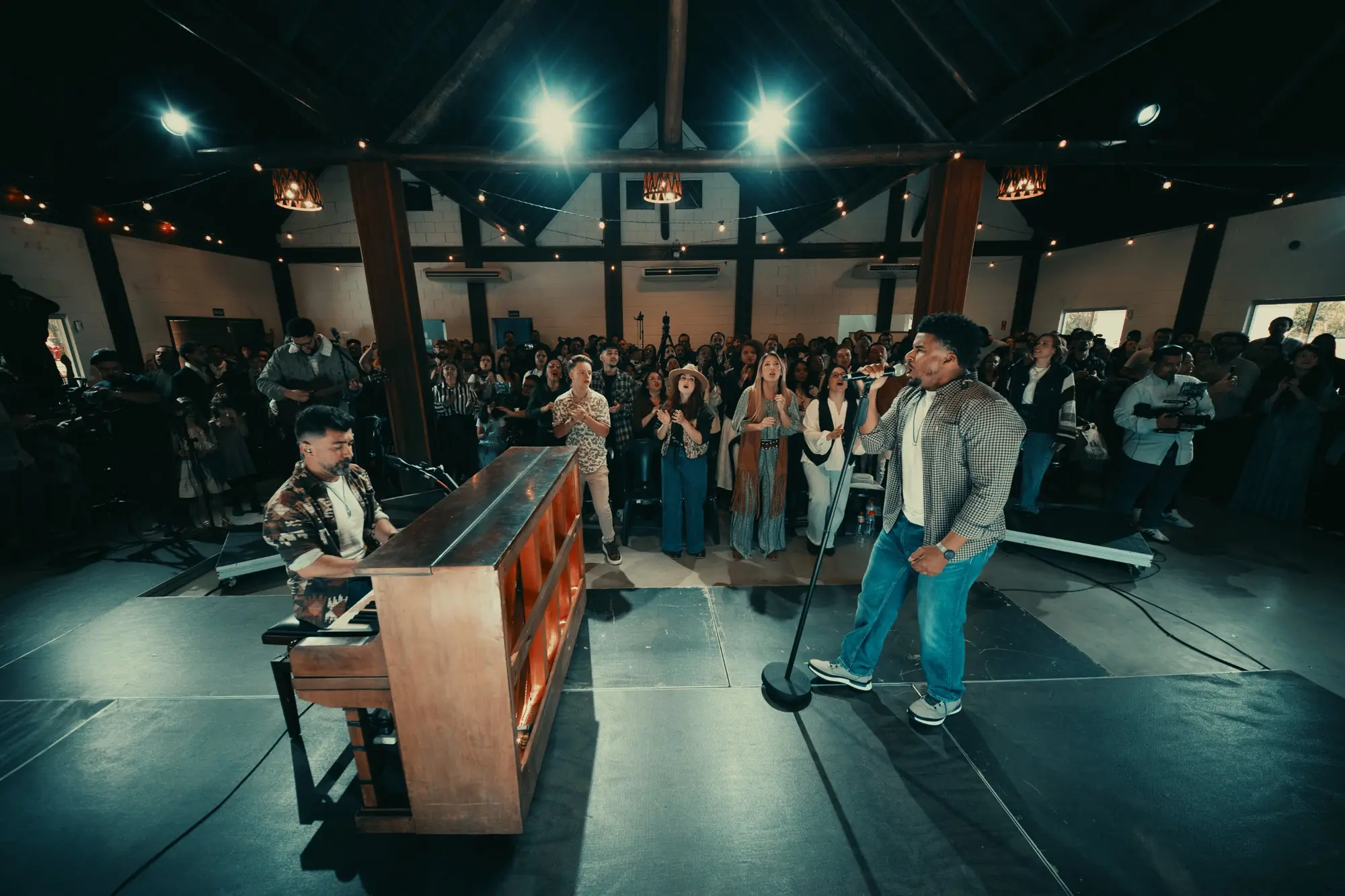 Cantor ministrando ao vivo no palco, com o piano ao lado